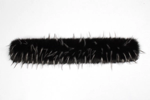 Détail d'un col en fausse fourrure noire avec pointes gris argenté sur fond blanc