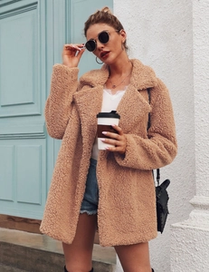 Detailed texture of light brown teddy faux fur coat with wide lapels and soft fabric