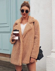 Outdoor shot of a woman in a long camel teddy coat with lapel collar and lace top