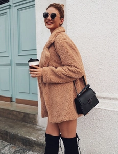 Detail view of caramel teddy faux fur coat styled with black rivet bag and boots