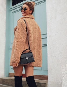 Detail of soft light tan teddy coat paired with a black studded flap crossbody bag