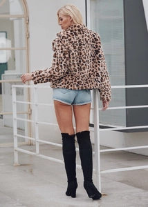 Détail de la texture d'un manteau en fausse fourrure léopard et manches longues stylées