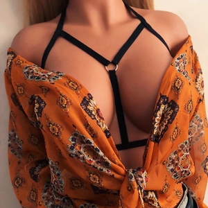 Sexy black cage body harness with silver metal rings worn under a bohemian printed blouse