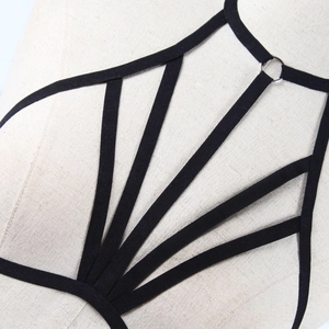 Macro view of black elastic harness straps with silver metal rings on a beige mannequin