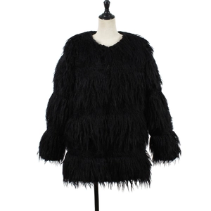 Détail macro de la texture de fausse fourrure noire et du col rond de ce manteau chic