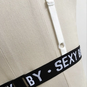 Détail de bretelle élastique avec lettrage 'BY · SEXY B' et boucle blanche réglable