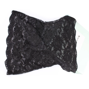 Détail de dentelle noire montrant la texture florale délicate et les bords festonnés