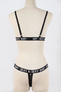 Detailansicht des schwarzen Spitzen-Lingerie-Sets mit SEXY BABY Buchstabenbändern