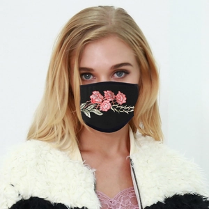 Detail of a black breathable fabric face mask with delicate pink rose embroidery design
