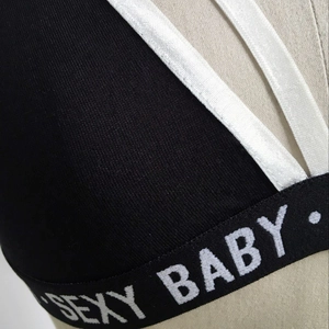 Détail d'un haut en tricot noir avec bande élastique lettrée SÉXY BABY blanche sur mannequin