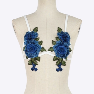 Close-up of intricate blue rose floral embroidery on a white lace bra with fine straps