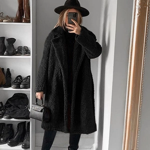 Detail of a black long faux fur teddy coat featuring a classic notched lapel collar
