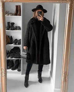 Detail of a black teddy fur long coat featuring a large lapel and thick fleece texture