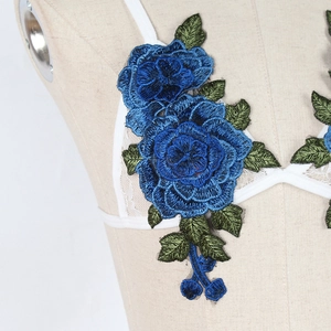 Close-up of 3D blue rose embroidery on white lace fabric with detailed floral texture