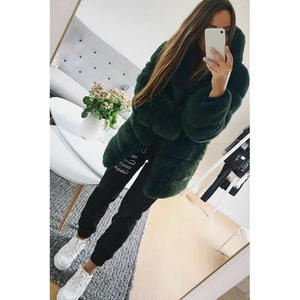 Detail view of dark green faux fur hooded coat showing plush texture and oversized fit design