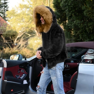 Men's winter black faux fur hooded coat with large brown fur trim on outdoor model