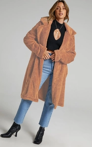 Detailed texture of caramel brown teddy plush coat styled with blue jeans and black boots