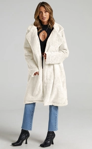 Detail view of white plush faux fur coat with oversized lapels and soft teddy texture
