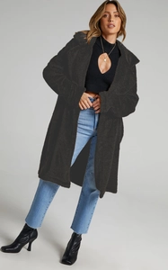 Detail of a black oversized faux shearling coat featuring a large lapel and cozy texture