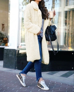 Close-up of cream faux fur teddy coat with thick warm texture and lapel pocket detail