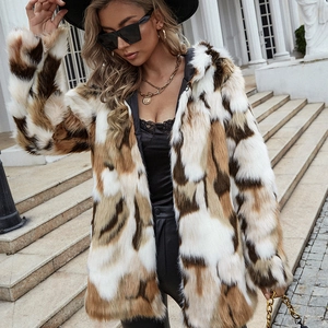 Woman in long faux fur coat with white and brown contrast patches on classic steps