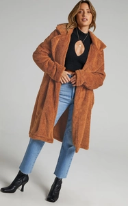 Full shot of long brown teddy plush coat styled with blue jeans and black boots
