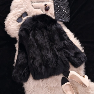 Giacca in finta pelliccia nera con accessori di lusso su tappeto di peluche rosa