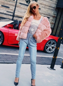 Close-up of pink faux fur jacket with ribbed stripes and high-waisted denim jeans