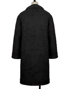 Macro detail of the thick black faux shearling texture on a long winter coat