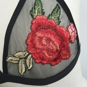 Close-up of red rose floral embroidery on black mesh triangle cup lingerie top