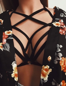 Detail of black cage harness with a metal ring paired with a floral kimono cardigan
