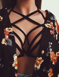 Detail of sexy black elastic harness with crossover straps and a metal ring connector