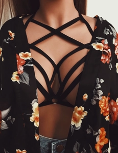 Detail of black caged bralette with cross straps paired with floral kimono and denim shorts