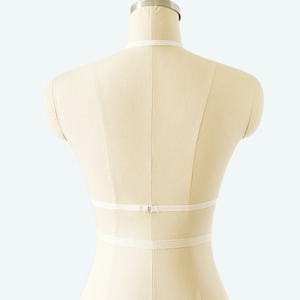 Detail view of white lace lingerie straps and buckle closure on a female mannequin torso