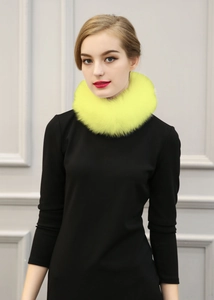 Détail d'un tour de cou en fausse fourrure jaune vif sur un pull noir élégant