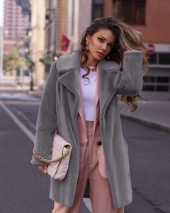 Oversized grey faux fur coat with large lapels styled over a pink suit in an urban setting
