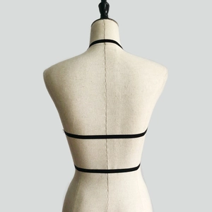 Detailed back view of elastic black body harness straps on a mannequin display
