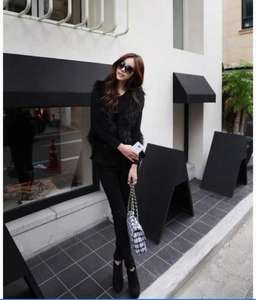 Street style view of a black faux fox fur vest for women over a long sleeve top