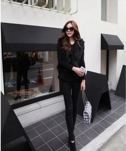 Outdoor street style showing a black faux fox fur vest with long sleeves and pants