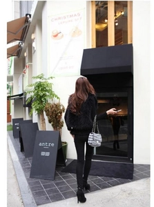 Street style view of a black faux fox fur vest paired with a classic plaid chain handbag