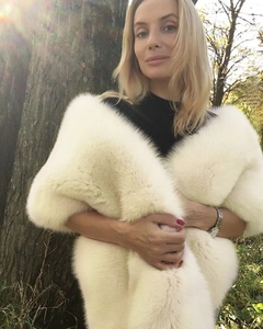 Detailed texture of ivory faux fur shawl worn by model in natural sunlight forest setting