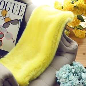 Detail view of plush faux fur yellow scarf with long soft fibers on a tufted chair