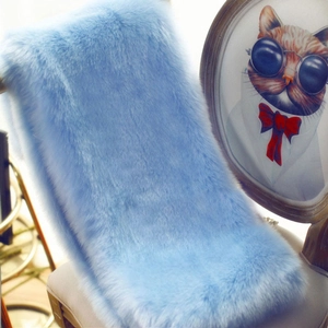 Close-up of soft light blue faux fur shawl with dense texture on a wooden chair
