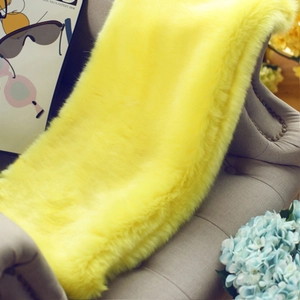 Detailed texture of fluffy bright yellow faux fur shawl draped over a gray sofa chair