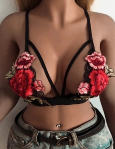 Detailed close-up of intricate red rose embroidery on a black lace halter bralette top
