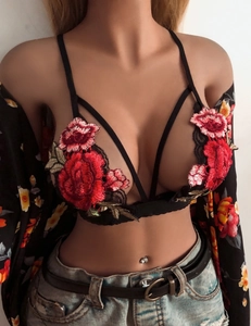 Close-up of black lace bra featuring red rose embroidery and intricate crisscross straps