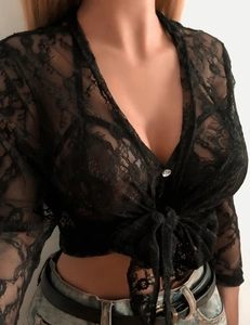 Détail d'un cardigan en dentelle noire avec nœud et bouton en strass brillant