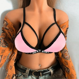 Detailed view of pink bra with black sexy baby lettering straps and floral shirt