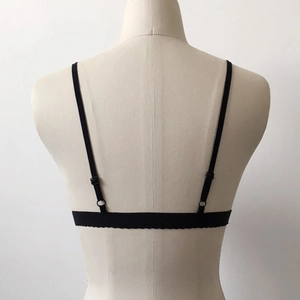 Detail of adjustable thin straps and delicate lace trim on the back of a black lace bra