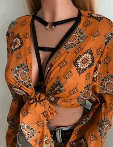 Gros plan du haut court bohème orange à fleurs avec nœud frontal et détails en dentelle noire
